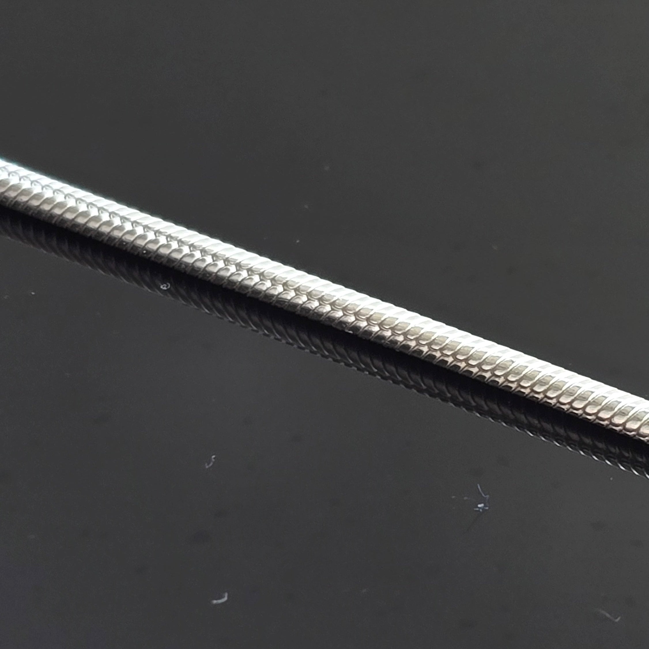 Close-up of silver round snake chain on  black background