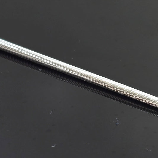 Close-up of silver round snake chain on  black background